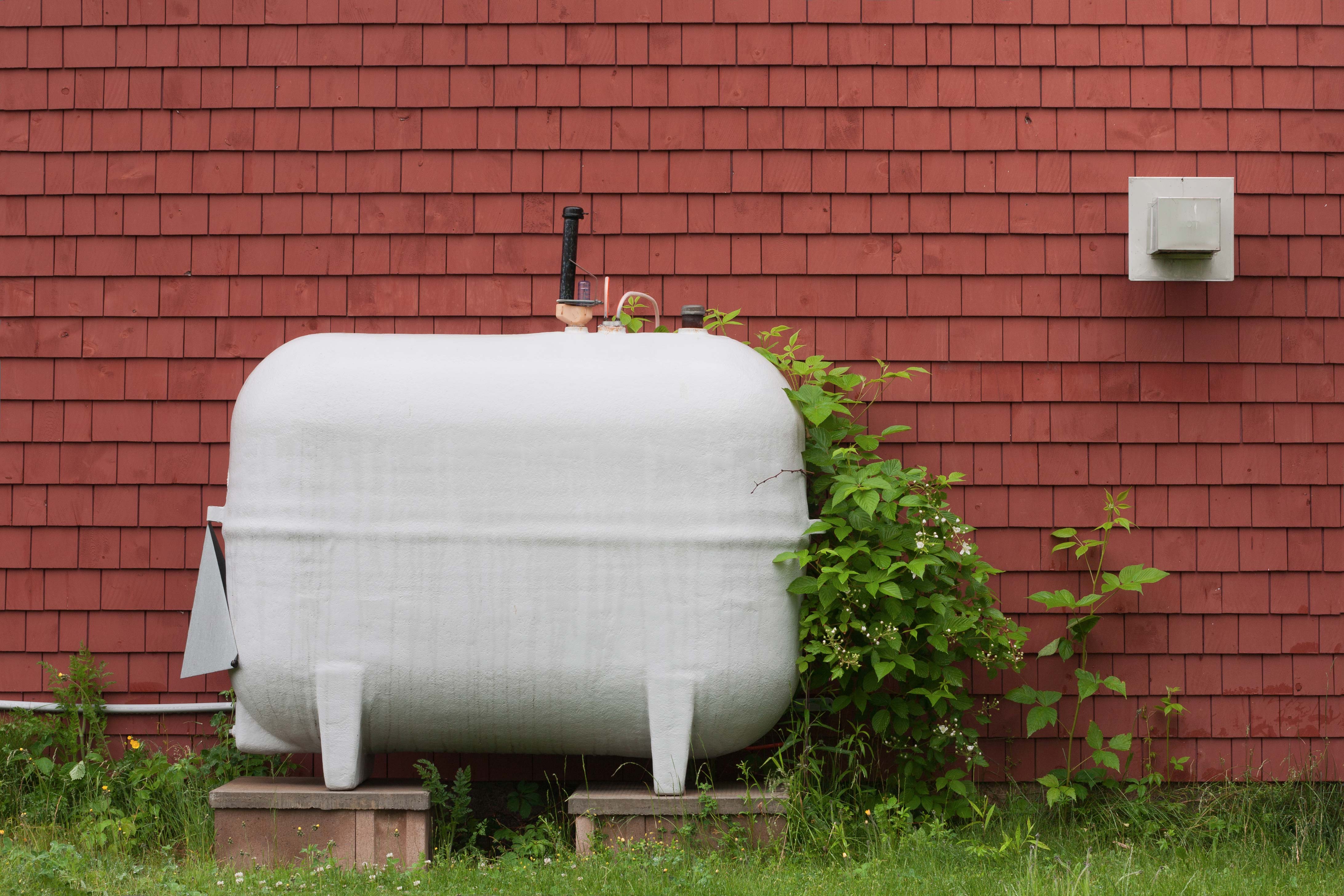 An oil tank standing in a garden, covered in handwritten stickers